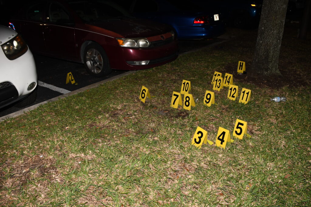 Crime scene photograph showing numbered yellow signs placed where police investigators found spent shell casings. from the shooting.